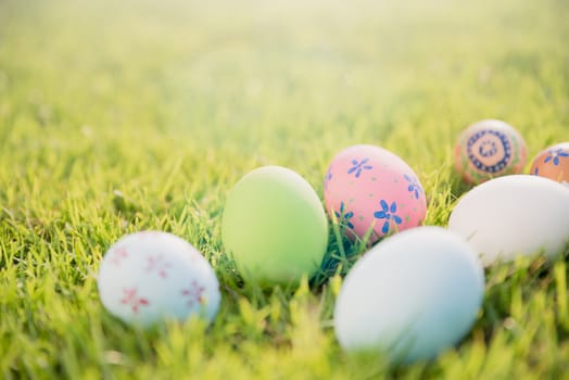 Happy easter!  Closeup Colorful Easter eggs on green grass field during sunset background.