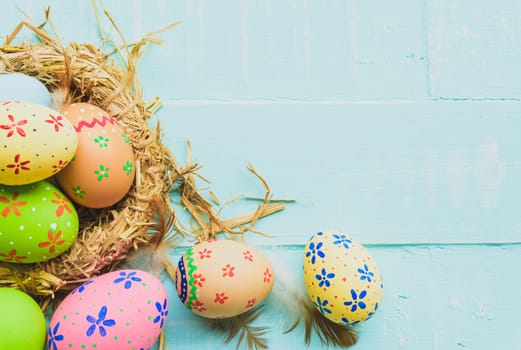 Happy easter! Colorful of Easter eggs in nest on pastel color bright green and white wooden background.