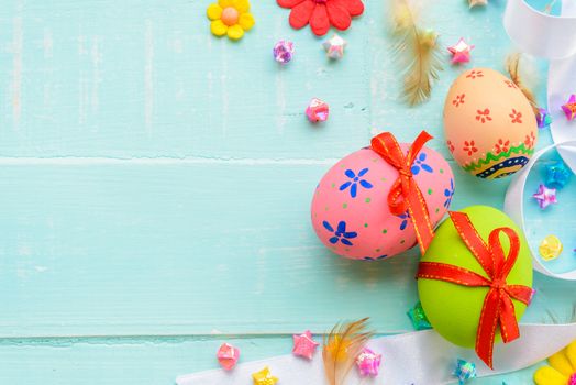 Happy easter! Colorful of Easter eggs with red ribbon and colorful of paper flower and paper star on pastel color bright green and white wooden background.