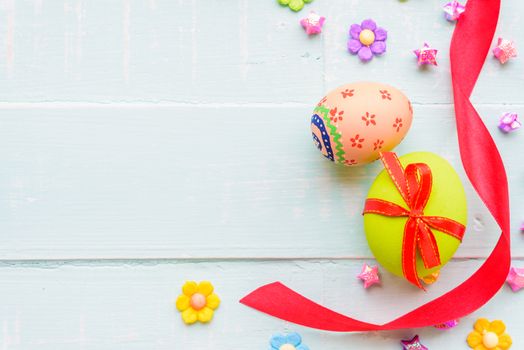 Happy easter! Colorful of Easter eggs with red ribbon and colorful of paper flower and paper star on pastel color bright green and white wooden background.