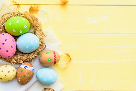 Happy easter! Colorful of Easter eggs in nest on pastel color bright green and white wooden background.