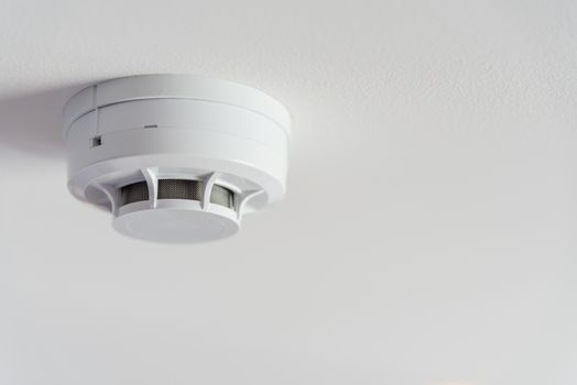 Close up smoke detector on a ceiling.