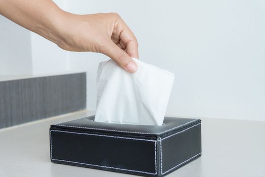 Woman hand picking white tissue paper from tissue box.