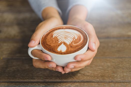 Woman hands holding cup of hot coffee latte cappuccino with heart shaped. Love, Wedding and Valentines day concept.