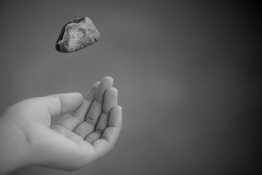 Young woman hand throwing stone on grass green background. Thinking and considering concept.