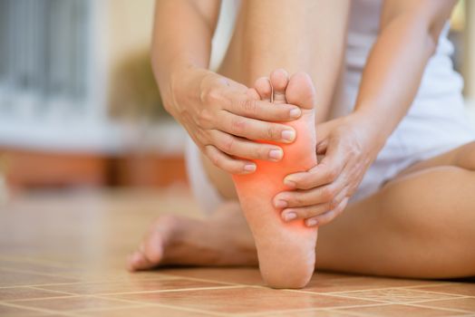 Closeup young woman feeling pain in her foot at home. Healthcare and medical concept.