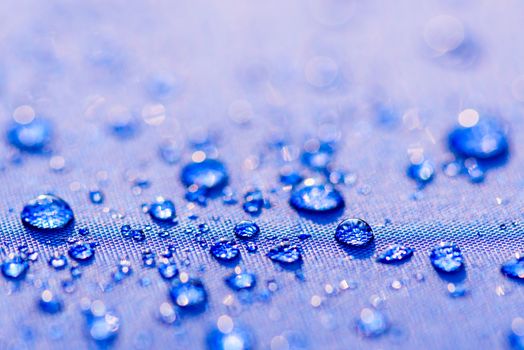 Close up Water drops pattern over a blue waterproof cloth background. World Water Day concept.