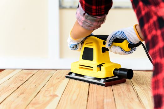 Womam Carpenter working with wood electrical sanding machine