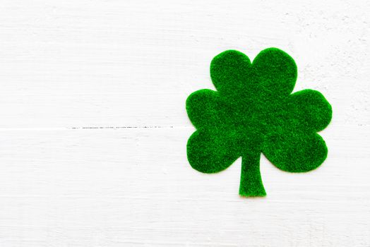 Happy St Patricks Day message on green paper clover and white wooden background