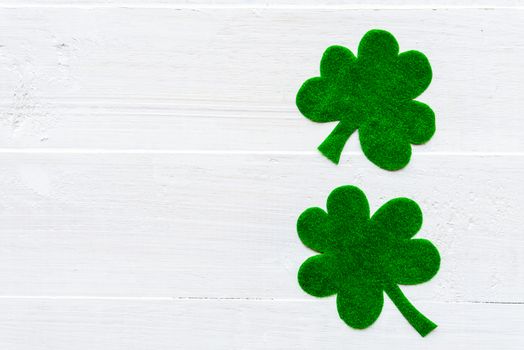 Happy St Patricks Day message on green paper clover and white wooden background