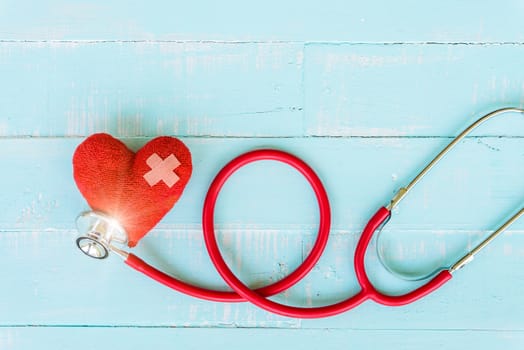 World health day, Healthcare and medical concept. Woman hand holding red heart with Stethoscope, notepad or notebook, thermometer and yellow Pill on Pastel white and blue wooden table background texture.