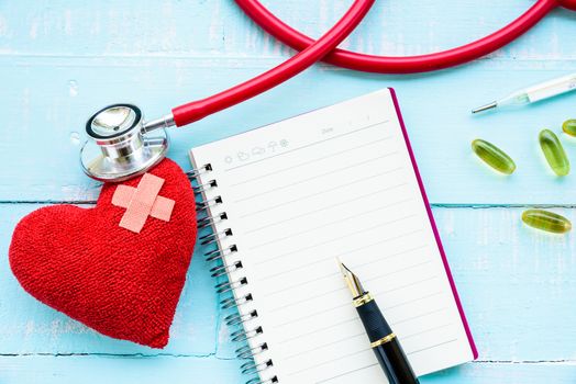 World health day, Healthcare and medical concept. Stethoscope, red heart, notepad or notebook, thermometer and yellow Pill on Pastel white and blue wooden table background texture.