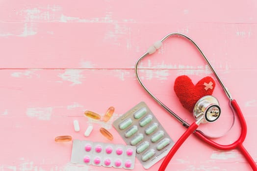 World health day, Healthcare and medical concept. Woman hand holding red heart with Stethoscope, notepad or notebook, thermometer and yellow Pill on Pastel white and blue wooden table background texture.