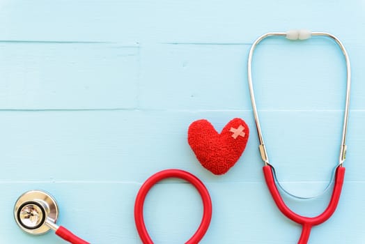 World health day, Healthcare and medical concept. Woman hand holding red heart with Stethoscope, notepad or notebook, thermometer and yellow Pill on Pastel white and blue wooden table background texture.