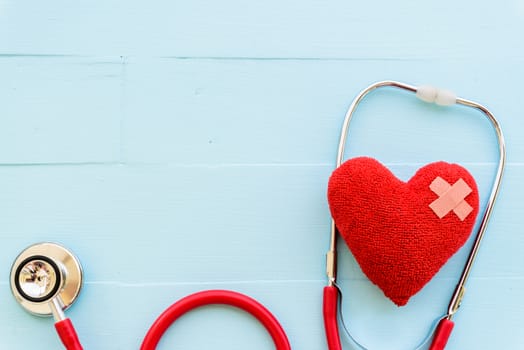 World health day, Healthcare and medical concept. Woman hand holding red heart with Stethoscope, notepad or notebook, thermometer and yellow Pill on Pastel white and blue wooden table background texture.