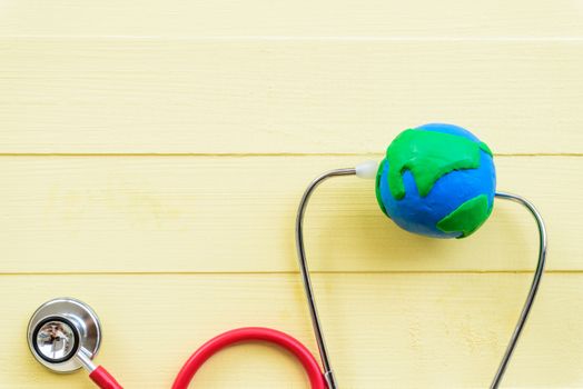 World health day, Healthcare and medical concept.  Stethoscope with handmade globe and Red heart on Pastel white and yellow wooden background.