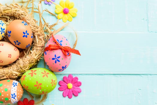 Happy easter! Colorful of Easter eggs in nest on pastel color bright green and white wooden background.