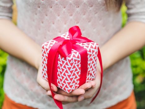 Female hand holding a gift box with red ribbon.  Love, valentine, christmas and new year concept.