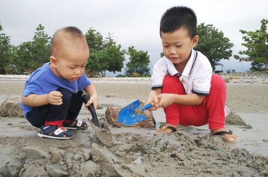 Asian children playing sand at beach side.