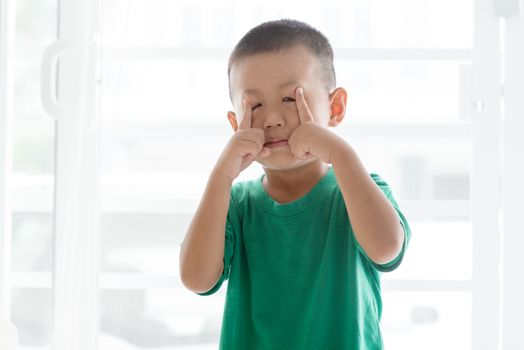 Young child at home. Playful Asian boy grimacing.
