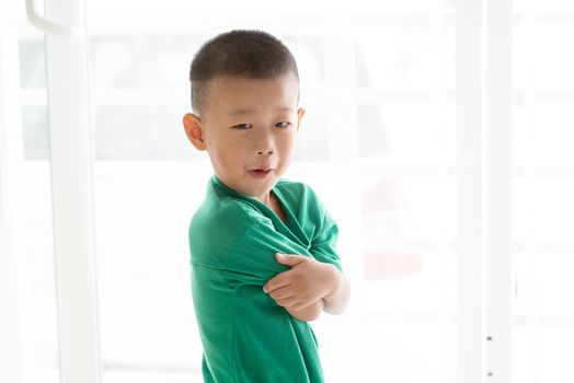 Young child at home. Playful Asian boy grimaces.