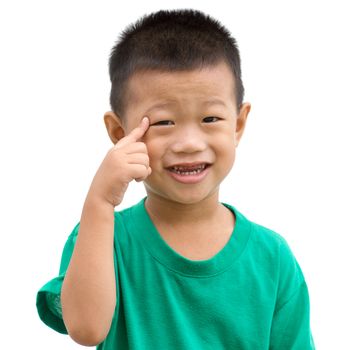 Happy Asian child smiling and pointing his eyes. Portrait of young boy showing body parts isolated on white background.