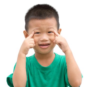 Happy Asian child pointing his eyes and smiling. Portrait of young boy showing body parts isolated on white background.