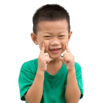 Happy Asian child smiling and pointing his cheeks. Portrait of young boy showing body parts isolated on white background.
