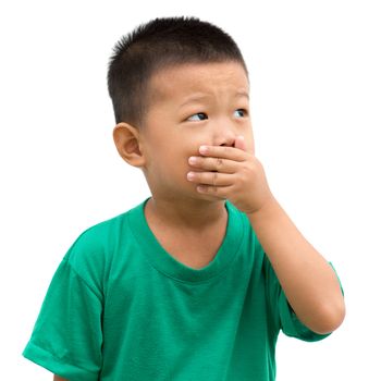 Asian child covering his mouth and looking to side. Portrait of young boy isolated on white background.