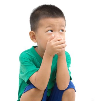 Asian child covering mouth with hands and looking away. Portrait of young boy isolated on white background.