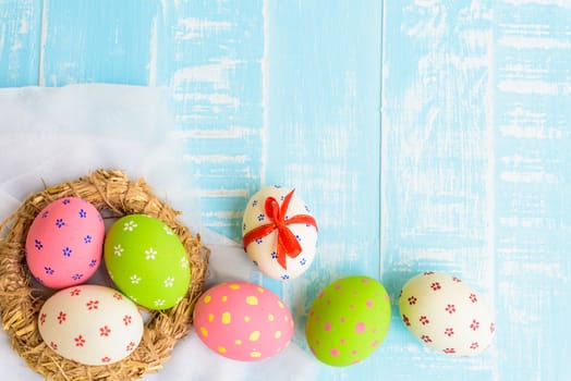 Happy easter! Colorful of Easter eggs in nest on pastel color bright green and white wooden background.