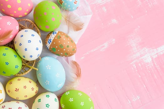 Happy easter! Colorful of Easter eggs in nest with paper star, flower and Feather on pastel color bright pink and white wooden background.