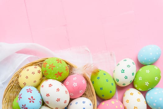 Happy easter! Colorful of Easter eggs in nest with paper star, flower and Feather on pastel color bright pink and white wooden background.