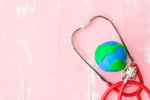 World health day, Healthcare and medical concept. Red heart with Stethoscope, handmade globe, thermometer and yellow Pill on Pastel white and pink wooden background.