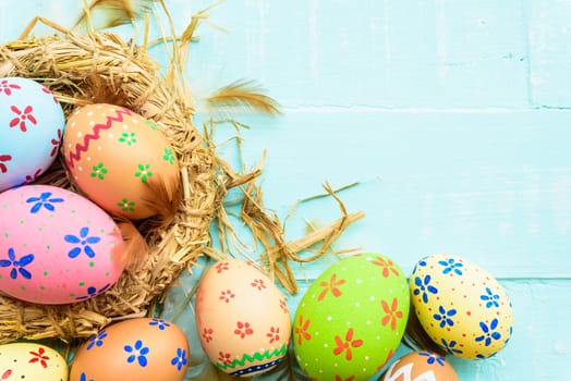 Happy easter! Colorful of Easter eggs in nest on pastel color bright green and white wooden background.