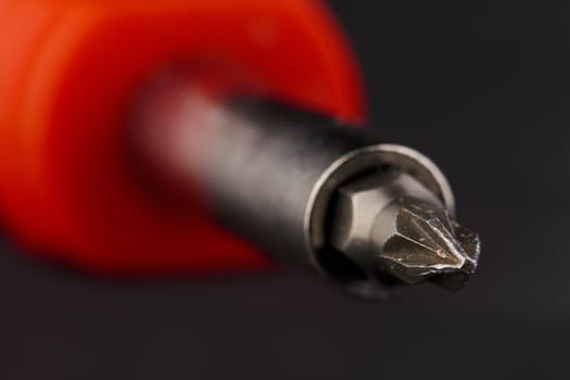 close-up of a screwdriver with red handle on black background