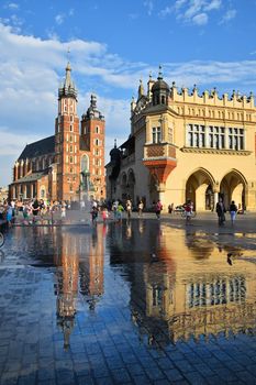 Low angle view of Main Market Square with town hall and Church of Our Lady Assumed into Heaven (Saint Mary Church after rain in Krakow, Poland