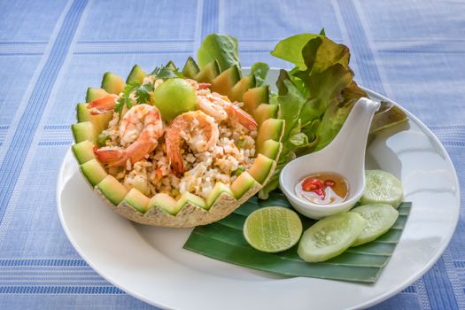 fried rice with shrimps in melon bowl served with fresh cucumber, lettuce, lime  and spicy fish sauce