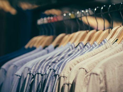 Close up view of man clothes hang in clothes store. Hangers with different male clothes. Copy space. Selective focus. Toned image