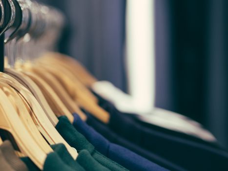 Close up view of man clothes hang in clothes store. Hangers with different male clothes. Copy space. Selective focus. Toned image