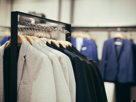 Close up view of man clothes hang in clothes store. Hangers with different male clothes. Copy space. Selective focus. Toned image