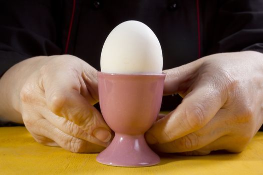 Boiled egg in the holder and the hands of the cook