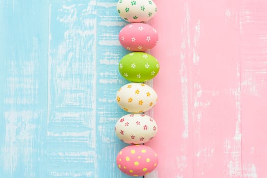 Happy easter! Row Easter eggs with colorful paper flowers on bright pink and green wooden background.