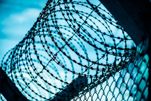 Closeup a security fence with barbed wire. Human Rights and social justice abstract concept.