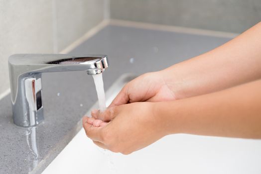 Selective focus of woman washing hands with soap under the faucet with water  in the bathroom.