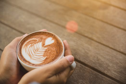 Woman hands holding cup of hot coffee latte cappuccino with heart shaped. Love, Wedding and Valentines day concept.