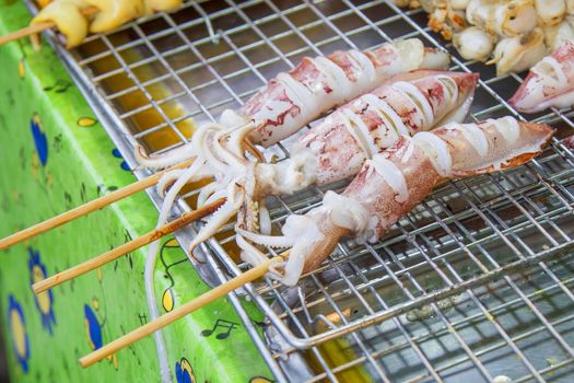 Grilled squid placed on a stainless steel sieve.