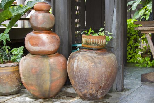 Old orange earthen jars stacked next to a wooden pole.