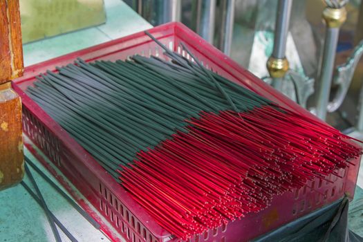 Many black incense sticks in a red basket.