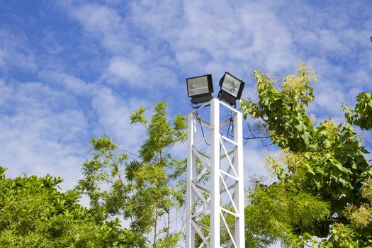 Spotlight pole with green tree With blue sky